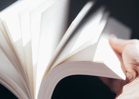 A close-up shot capturing a person's hand flipping through a bright white book.